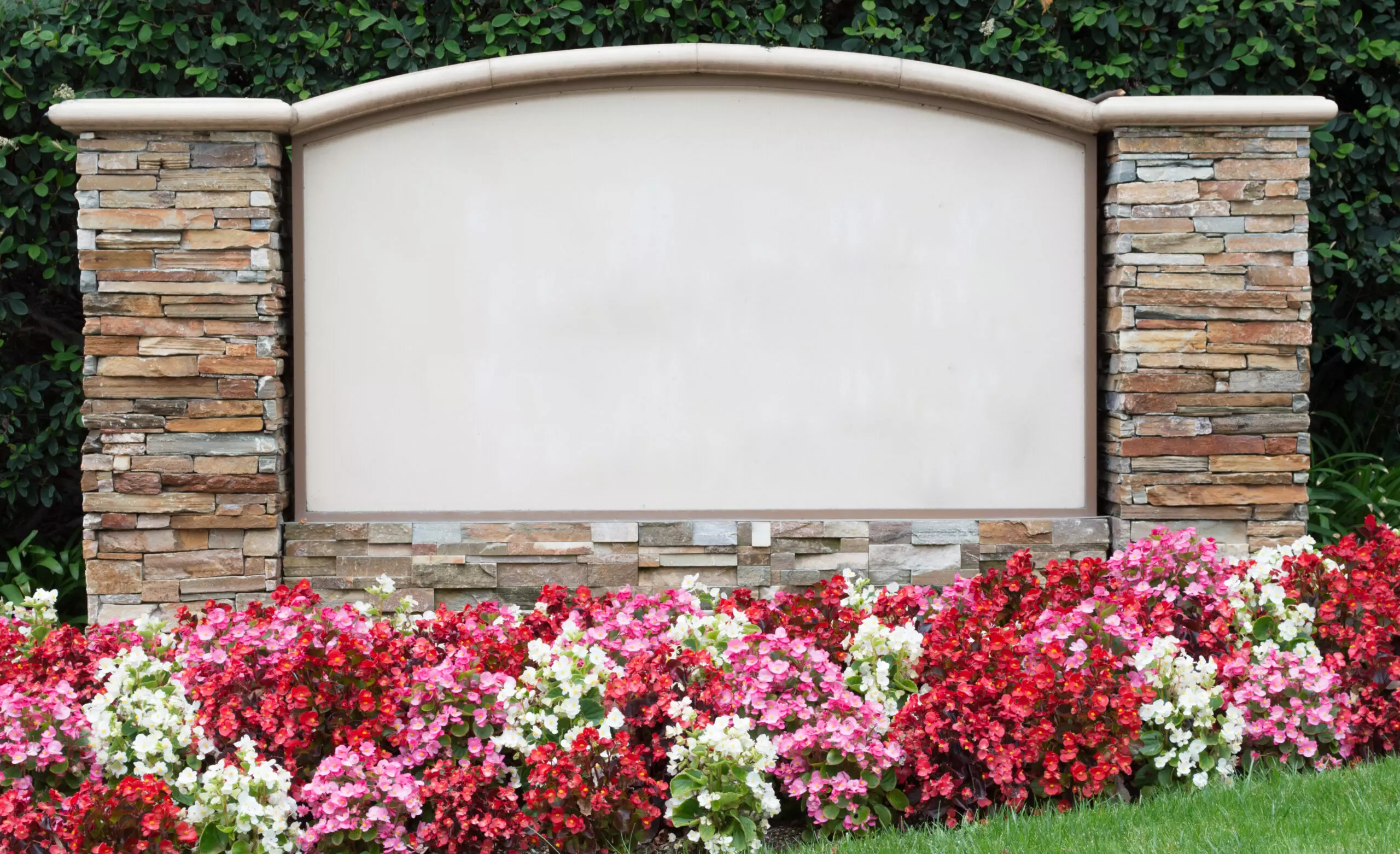 Blank stone sign marker with flowers in front