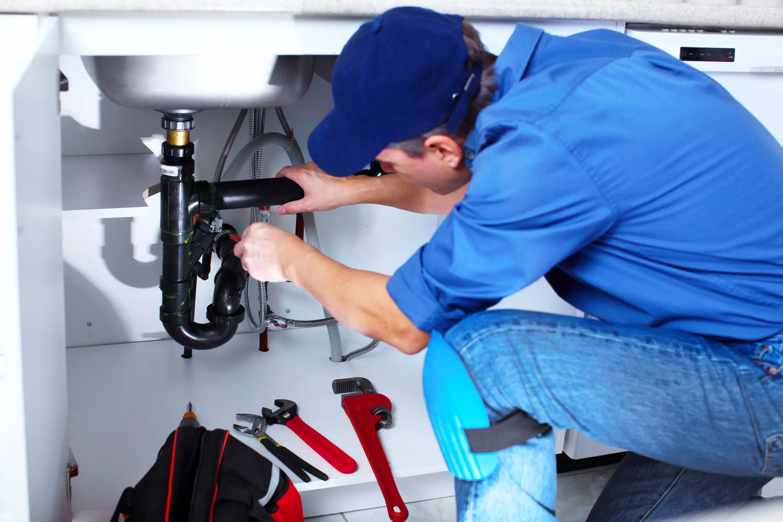 commercial plumbing services with professional plumber fixing sink
